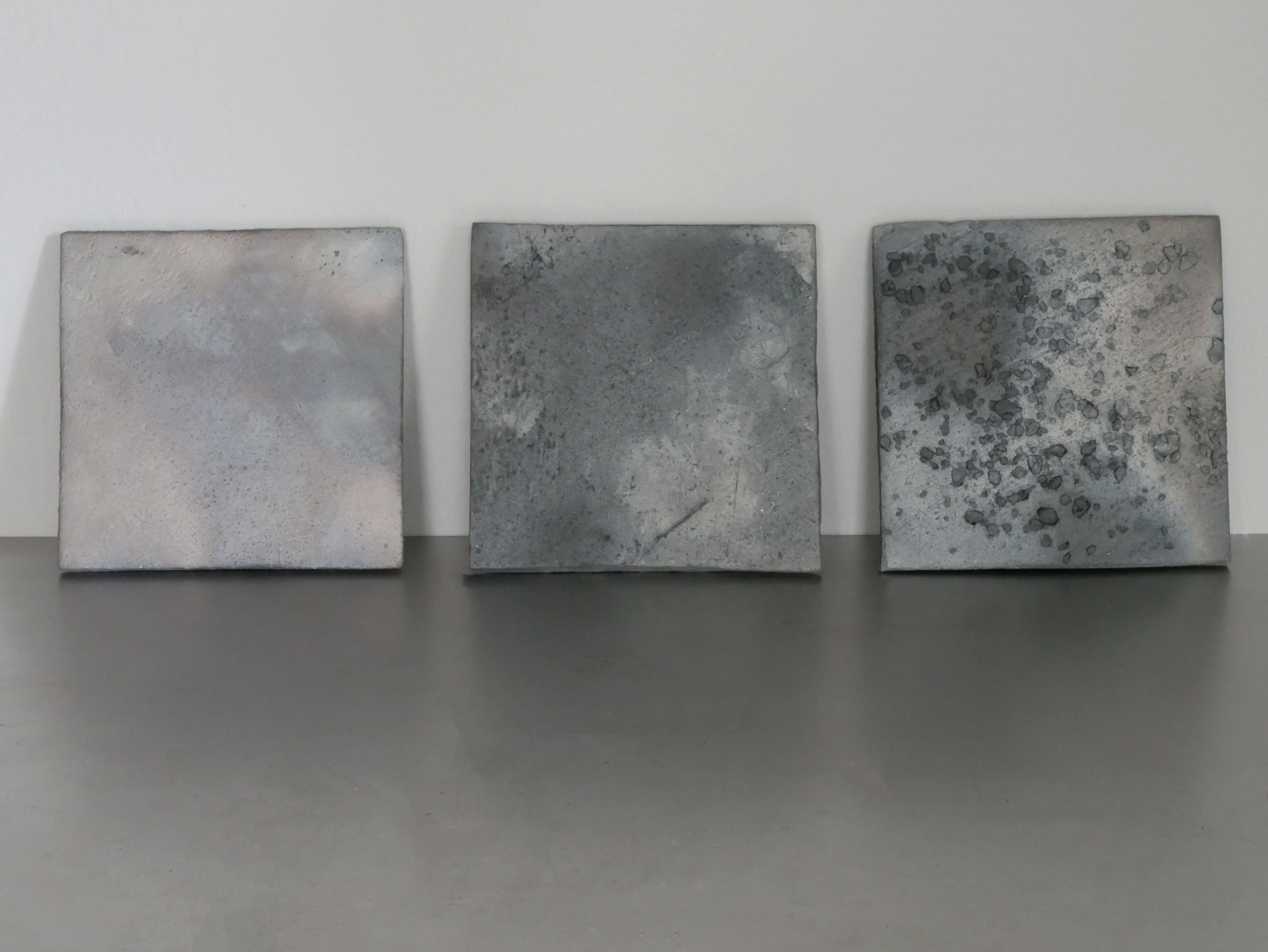 Three high-fired clay tiles, pale to grey to aggregate